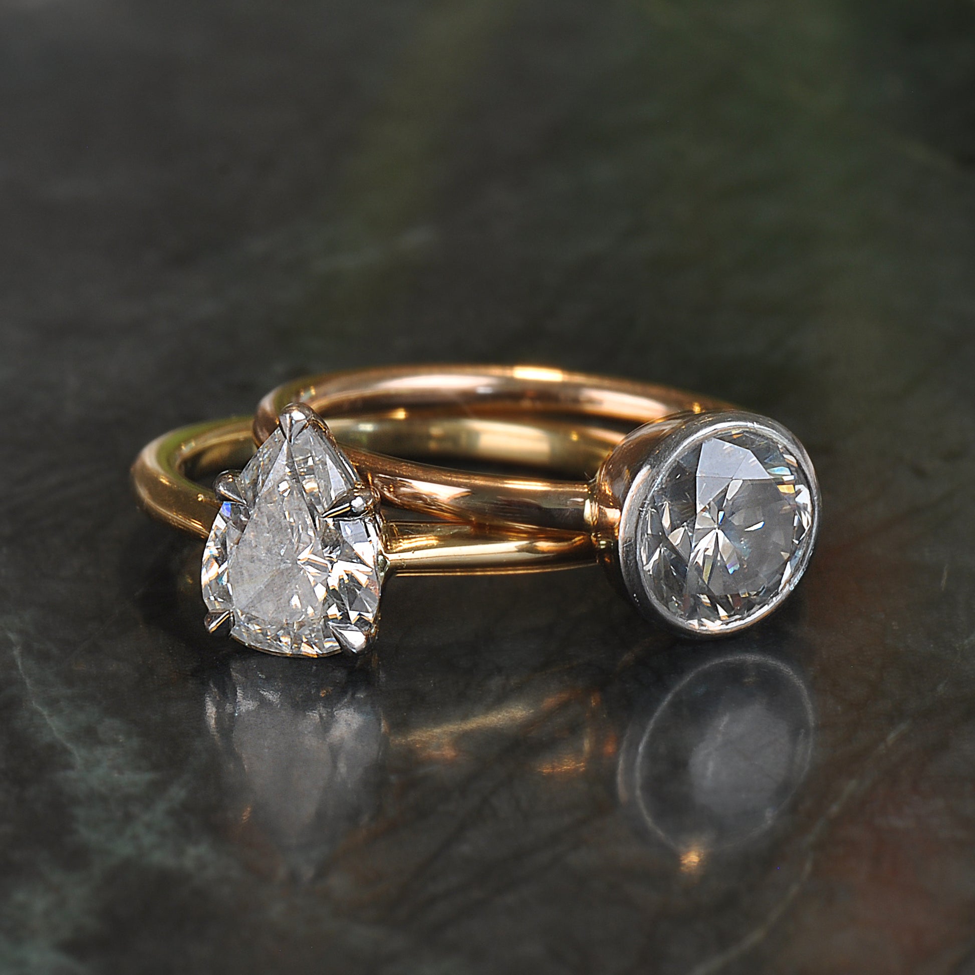 Two gold rings with diamond stones on a dark surface