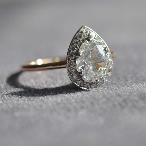 Diamond ring with a pear-shaped gemstone on a gray background
