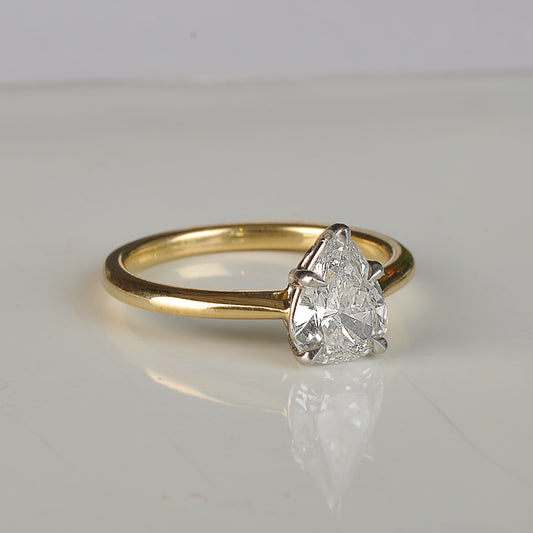 Gold ring with a pear-shaped diamond on a light gray background