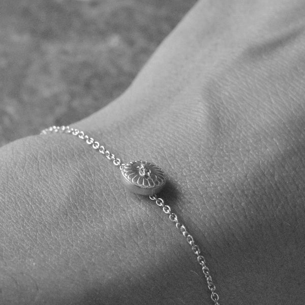 Silver bracelet with a unique clasp on a wrist against a neutral background