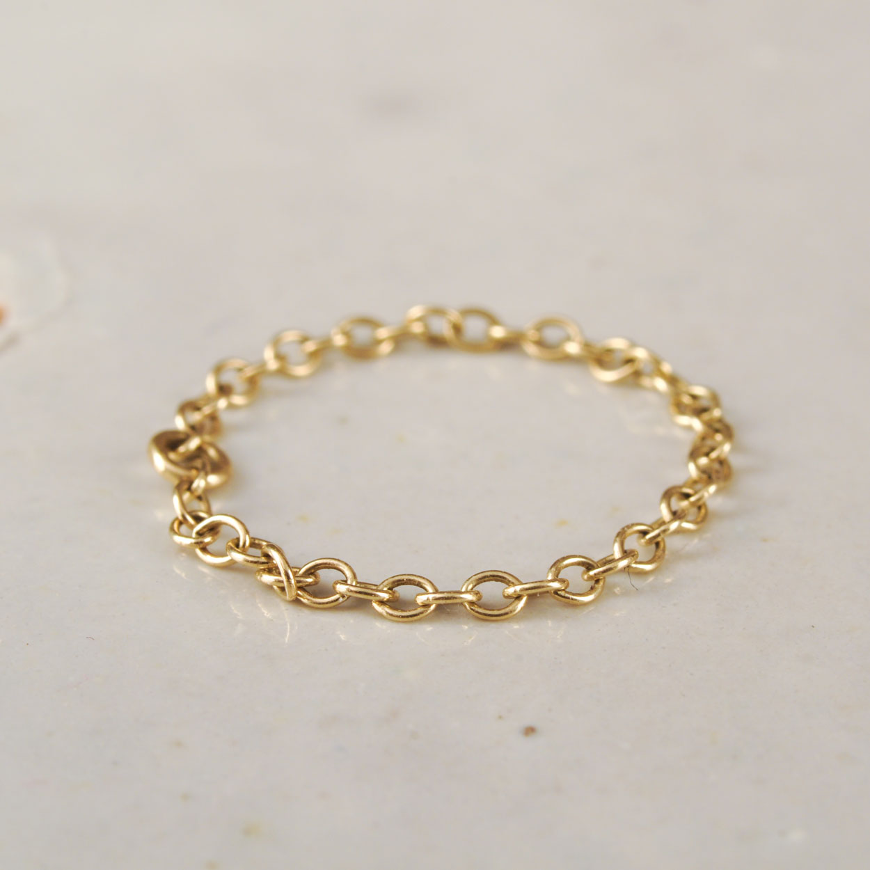 Gold chain ring on a light gray background