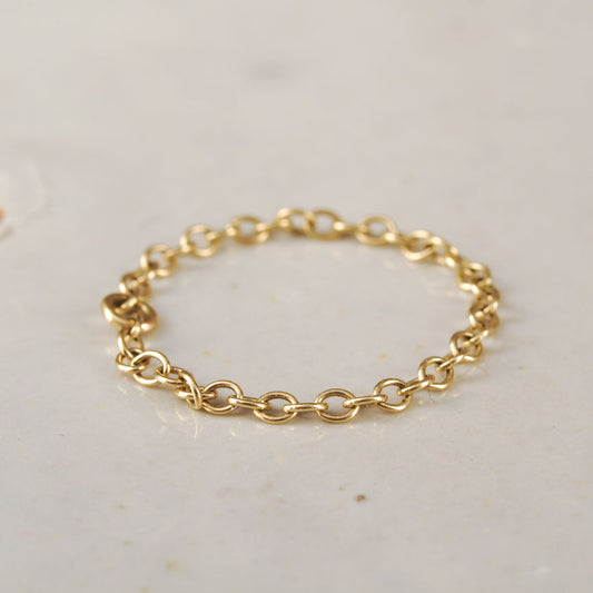 Gold chain ring on a light gray background