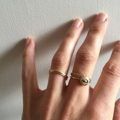 Hand wearing two gold rings on a light background