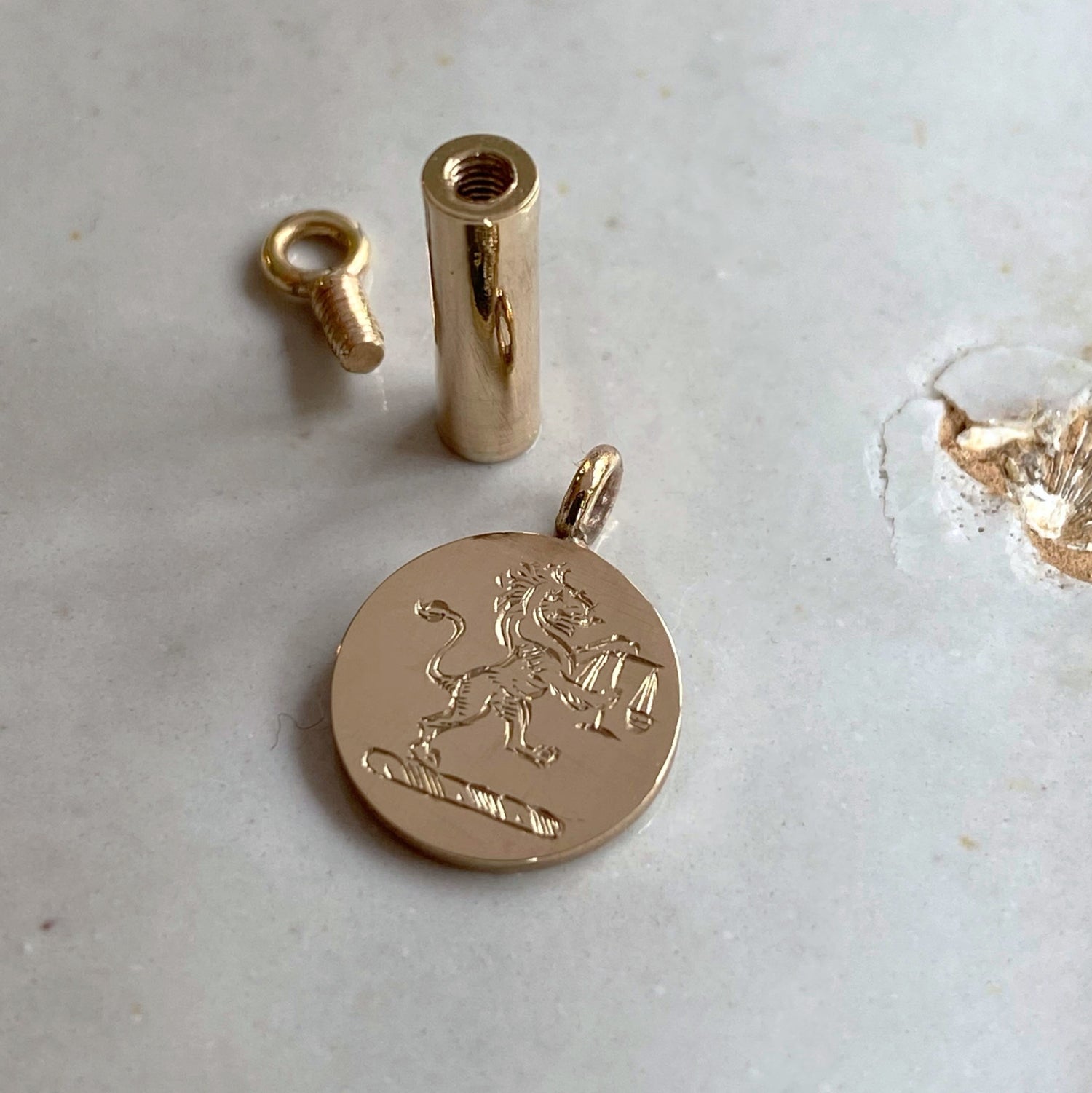 Gold pendant with a lion emblem on a light gray surface