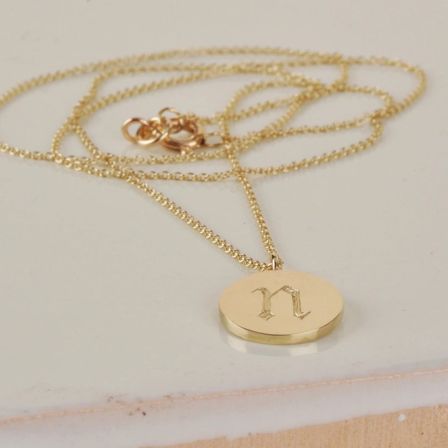 Gold necklace with a round pendant on a light background