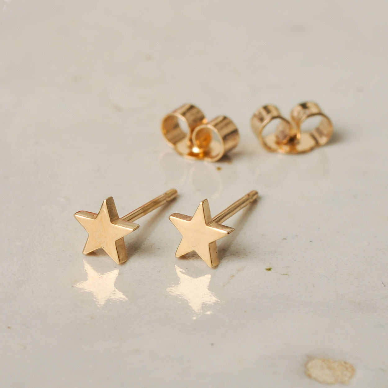 Gold star earrings on a light gray surface