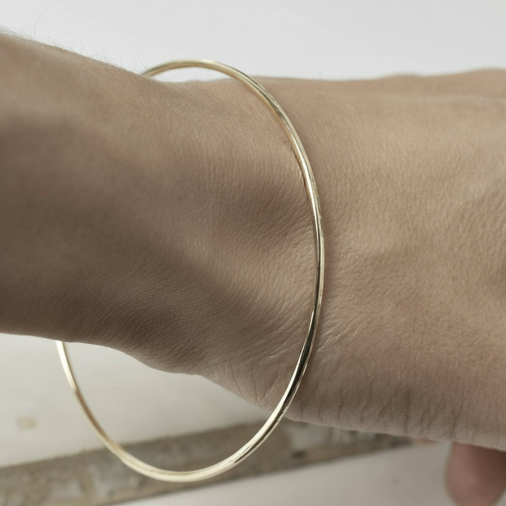 hammered yellow gold fine bangle on wrist
