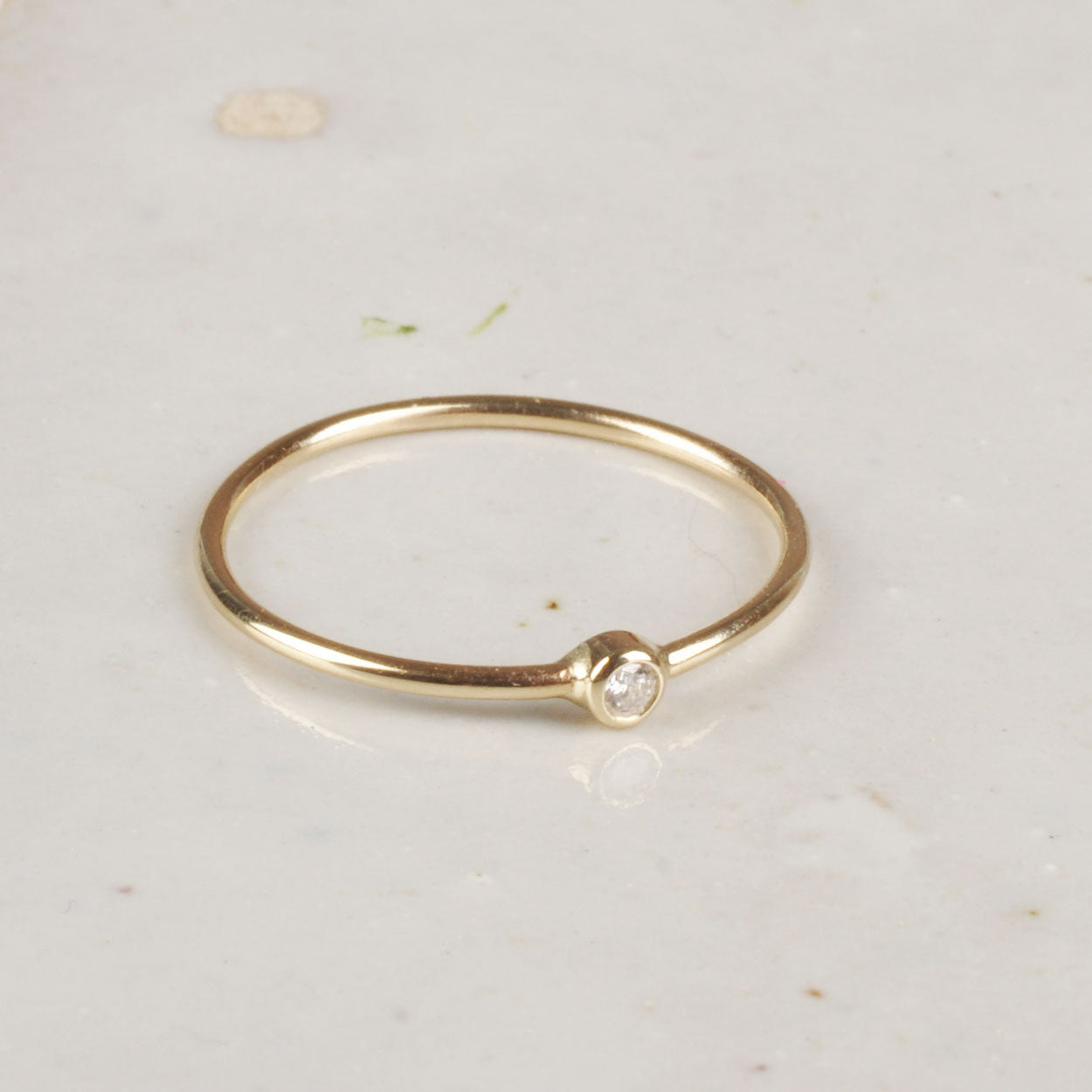 Gold ring with a small diamond on a light background