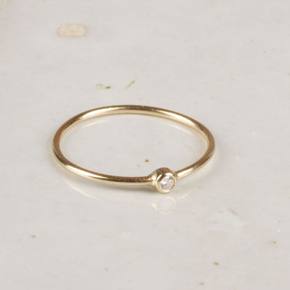 Gold ring with a small diamond on a light background