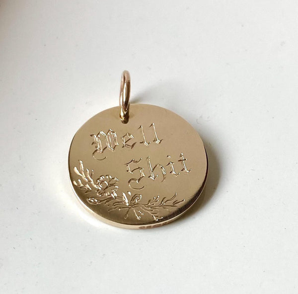 Gold pendant with engraved text on a white background